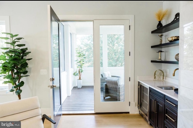 doorway with light wood-style flooring, wine cooler, and a sink