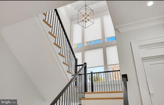 staircase with ornamental molding, recessed lighting, a towering ceiling, and a notable chandelier