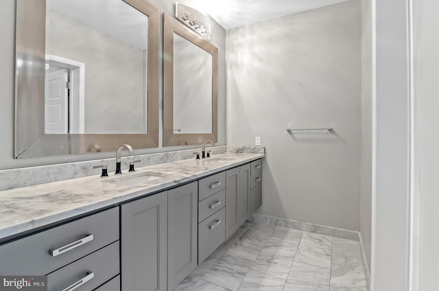 full bath with marble finish floor, a sink, baseboards, and double vanity