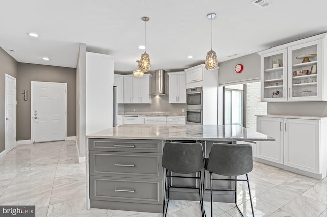 kitchen featuring double oven, white cabinetry, marble finish floor, wall chimney exhaust hood, and glass insert cabinets