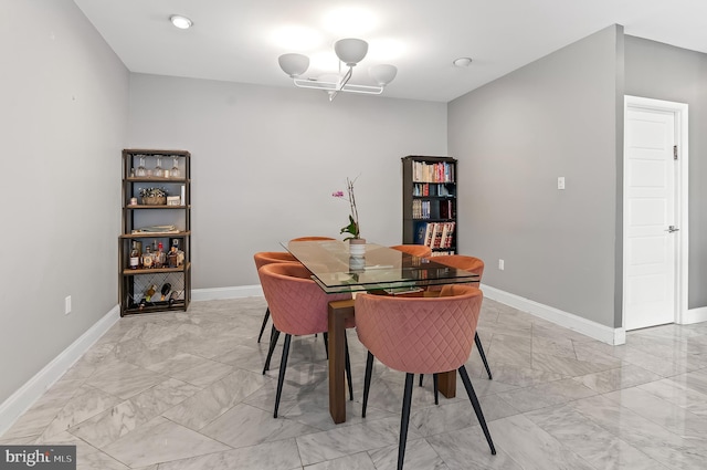 dining area featuring marble finish floor, a notable chandelier, and baseboards