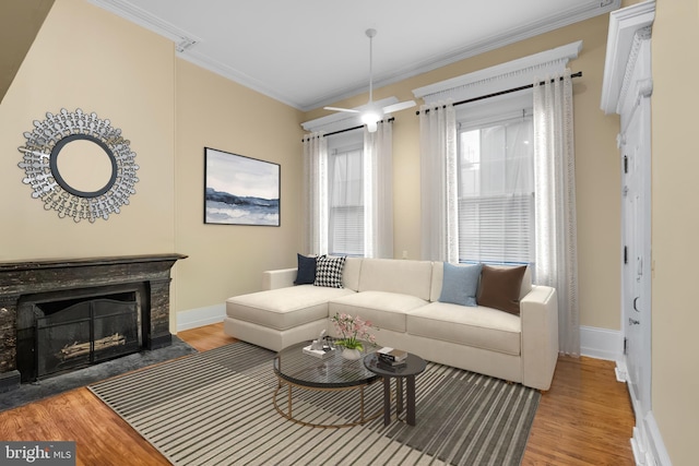 living area featuring wood finished floors, ornamental molding, a fireplace with flush hearth, and baseboards