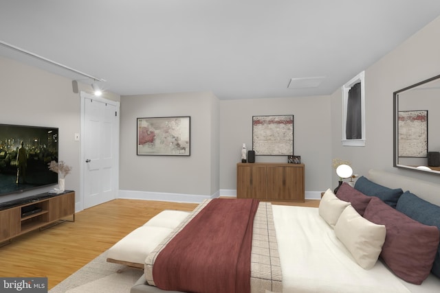 bedroom with track lighting, baseboards, and wood finished floors