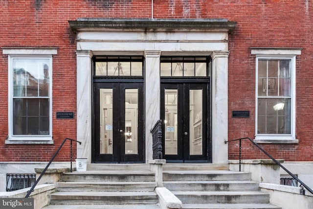 view of exterior entry featuring french doors and brick siding