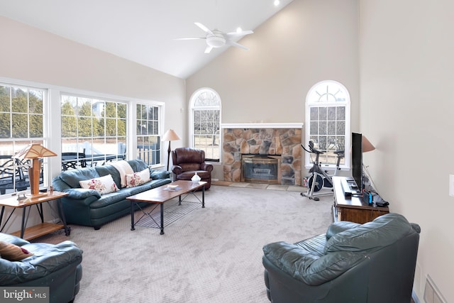 living room with a healthy amount of sunlight, a fireplace, high vaulted ceiling, and carpet flooring