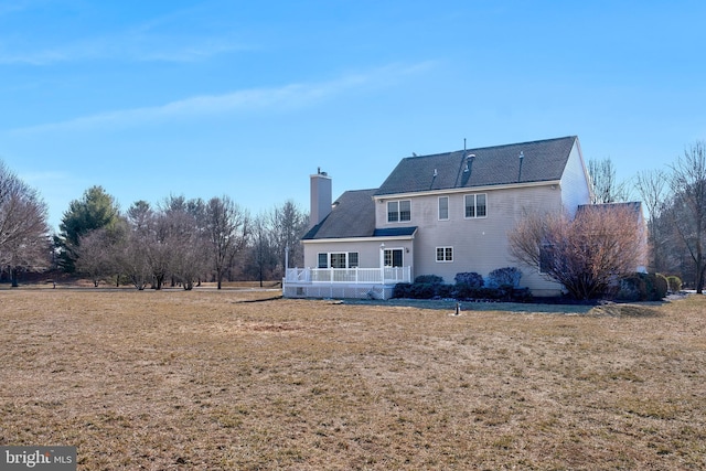 rear view of property featuring a lawn and a chimney