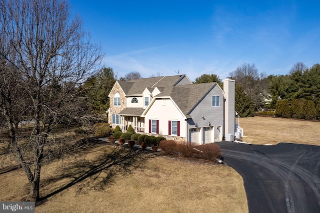 view of front of home with driveway, a chimney, and an attached garage