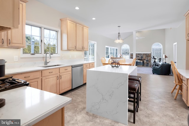 kitchen with a kitchen bar, light brown cabinets, stainless steel dishwasher, and a center island