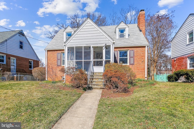 view of front of property with brick siding, a front lawn, fence, a chimney, and a sunroom