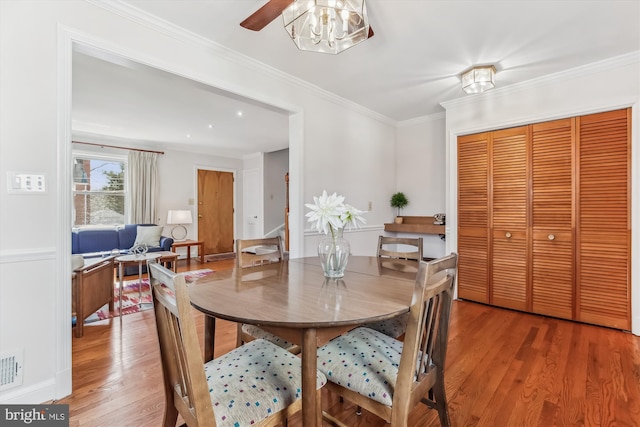 dining area with visible vents, light wood finished floors, and ornamental molding