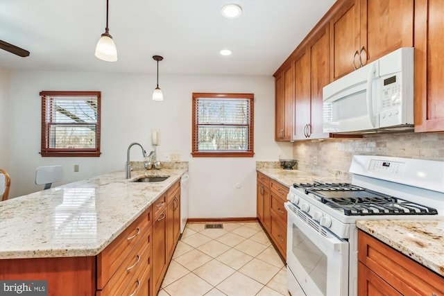 kitchen featuring brown cabinets, a sink, white appliances, a peninsula, and decorative backsplash