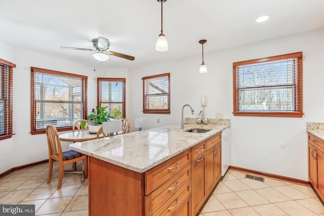 kitchen featuring brown cabinets, a sink, decorative light fixtures, a peninsula, and dishwasher