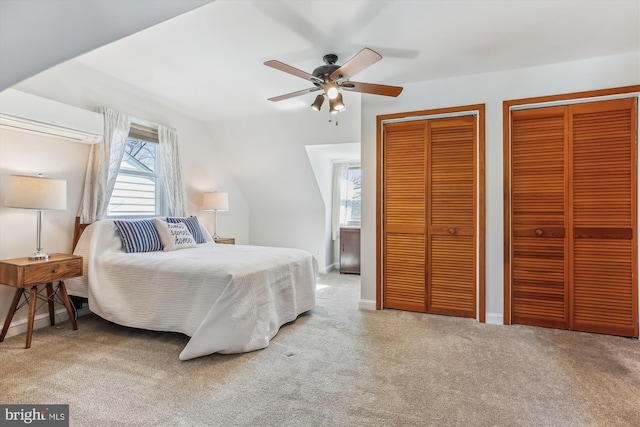 carpeted bedroom featuring ceiling fan, baseboards, a wall unit AC, and multiple closets