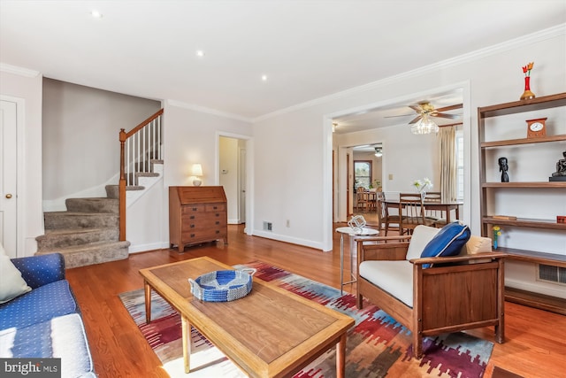 living area featuring visible vents, ornamental molding, stairs, and wood finished floors