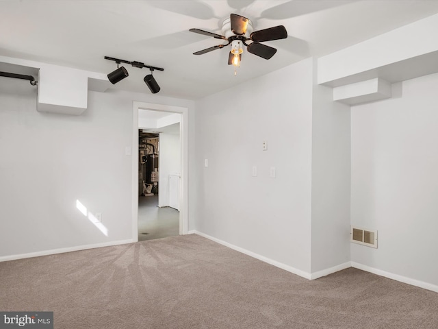 carpeted empty room with rail lighting, visible vents, ceiling fan, and baseboards