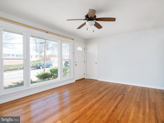 spare room featuring a ceiling fan, baseboards, and light wood finished floors