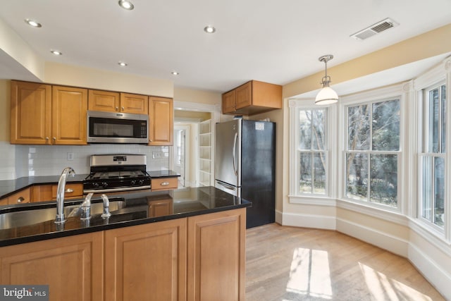 kitchen featuring a sink, visible vents, appliances with stainless steel finishes, light wood finished floors, and tasteful backsplash