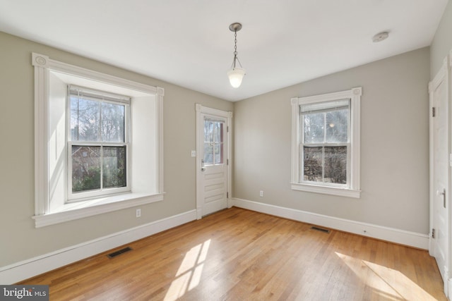 entrance foyer featuring a wealth of natural light, visible vents, baseboards, and wood finished floors