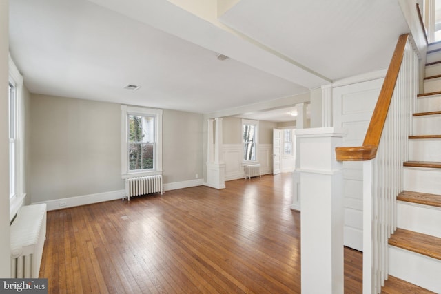 interior space featuring wood-type flooring, visible vents, and radiator heating unit