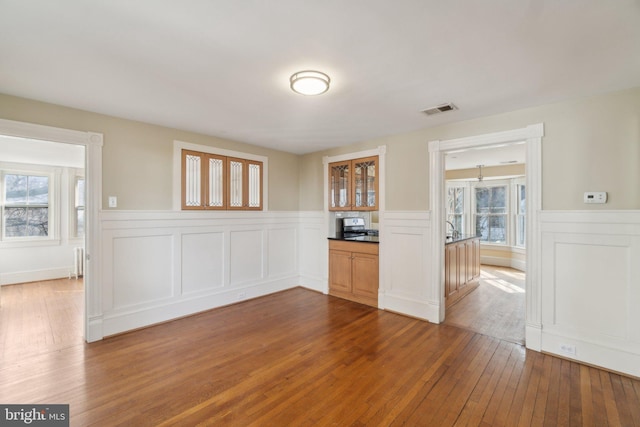 spare room with a wainscoted wall, dark wood-type flooring, and visible vents