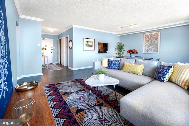 living room featuring a textured ceiling, wood finished floors, baseboards, rail lighting, and crown molding