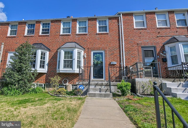 multi unit property with brick siding and a front yard