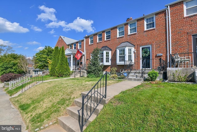 view of front facade with brick siding and a front lawn