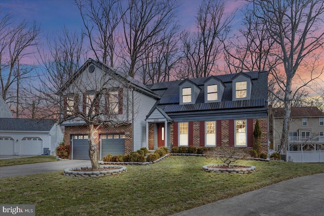 view of front facade featuring a garage, brick siding, a yard, driveway, and roof mounted solar panels