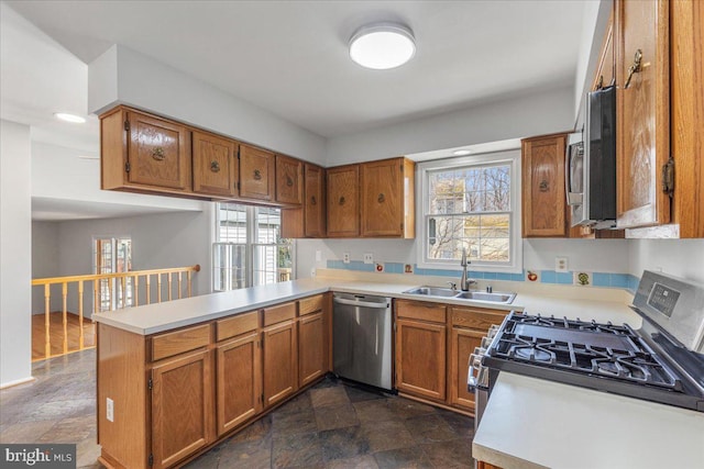 kitchen with stainless steel appliances, a sink, light countertops, and brown cabinets