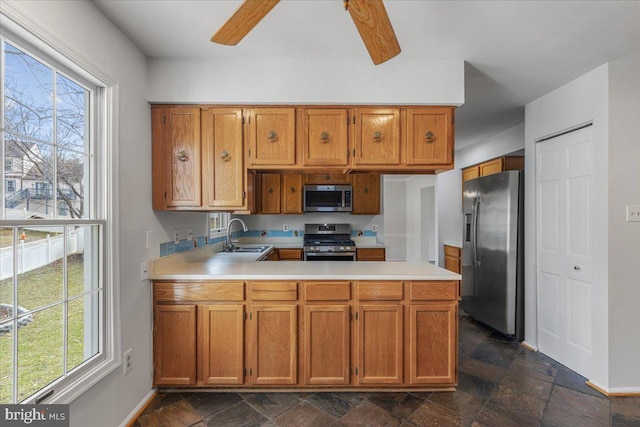 kitchen with a peninsula, appliances with stainless steel finishes, a sink, and light countertops