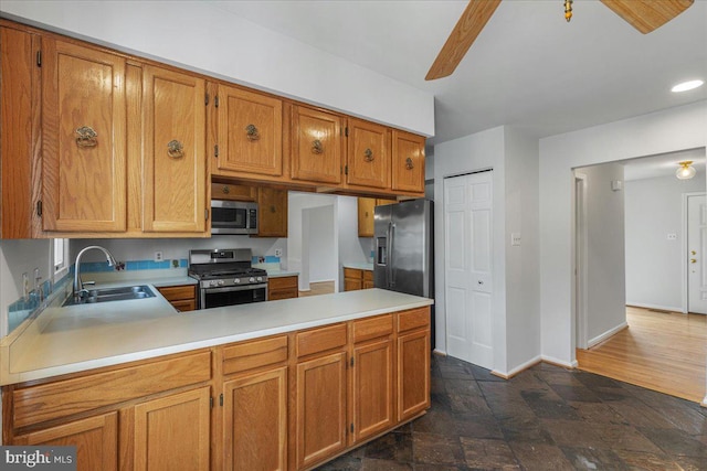 kitchen featuring appliances with stainless steel finishes, light countertops, a sink, and a peninsula