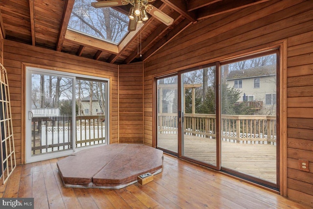 unfurnished sunroom featuring vaulted ceiling with beams, a wealth of natural light, and a ceiling fan