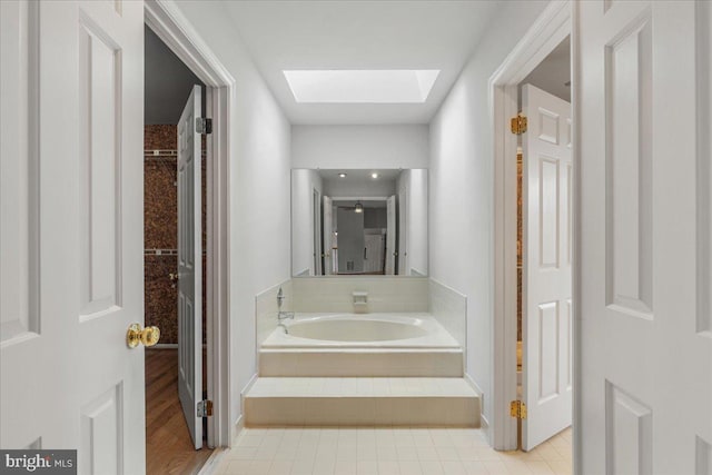 full bathroom with a skylight, a garden tub, and tile patterned floors