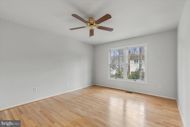 spare room with visible vents, ceiling fan, baseboards, and wood finished floors