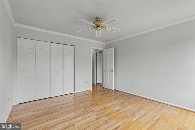 unfurnished bedroom with crown molding, a closet, baseboards, and light wood-style floors