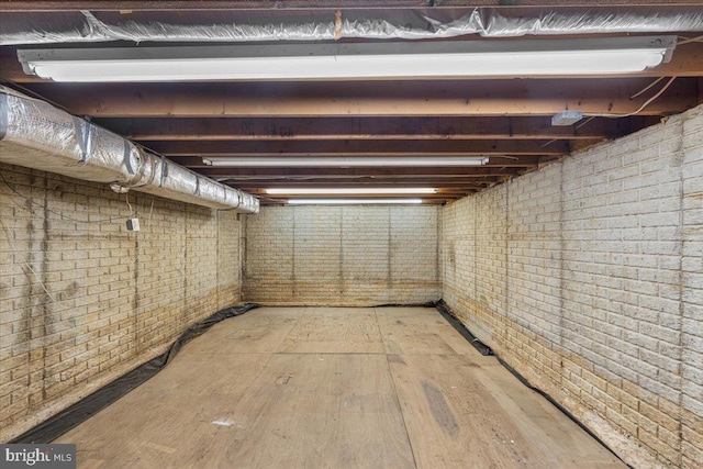 unfinished below grade area featuring light wood-style floors and brick wall