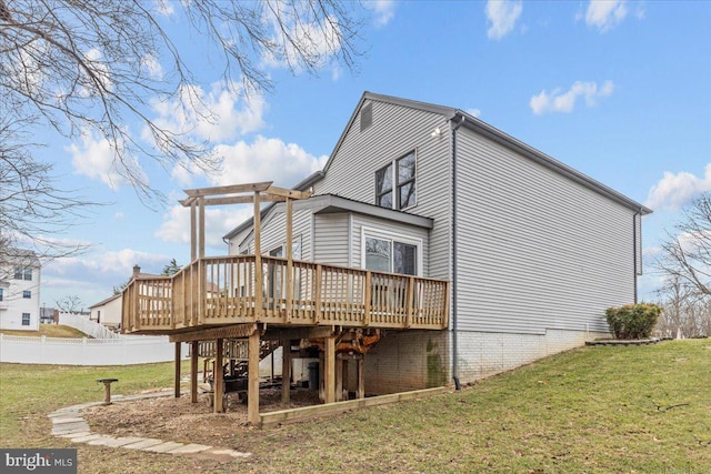 back of property with fence, a lawn, and a wooden deck