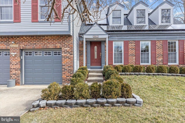 property entrance with brick siding, driveway, an attached garage, and a lawn