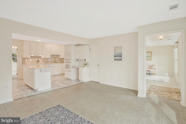 kitchen featuring white appliances, light tile patterned floors, visible vents, decorative backsplash, and light countertops