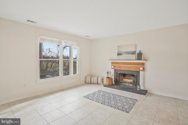 living room featuring a tile fireplace, visible vents, baseboards, and tile patterned floors