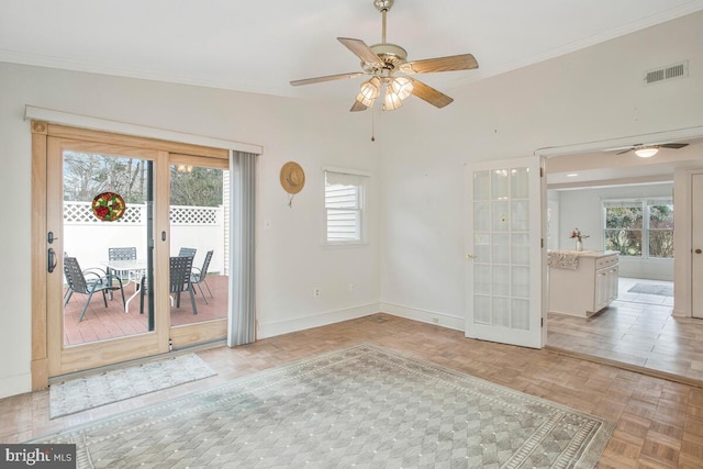 empty room with a ceiling fan, visible vents, crown molding, and baseboards