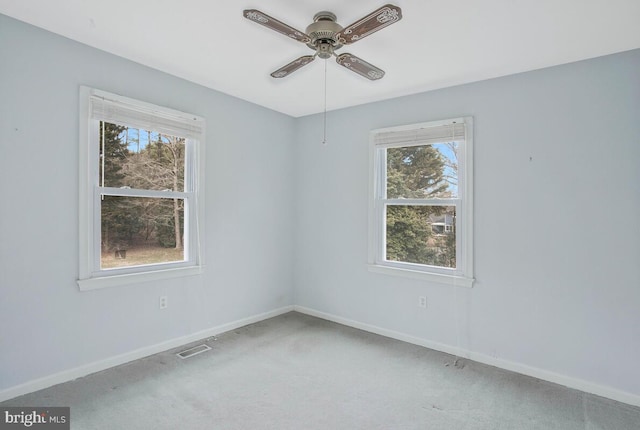 carpeted spare room with ceiling fan, visible vents, and baseboards