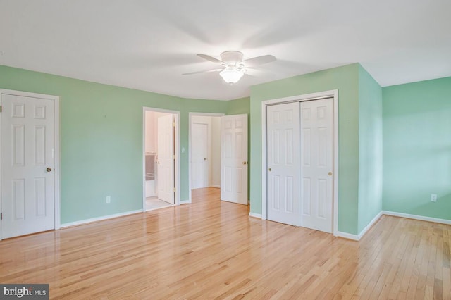 unfurnished bedroom featuring a closet, light wood-style flooring, ensuite bathroom, a ceiling fan, and baseboards