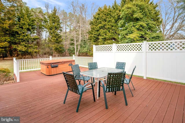 wooden deck with outdoor dining space, fence, and a hot tub