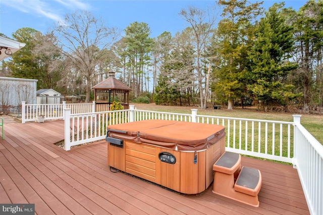 wooden terrace featuring a lawn, a hot tub, a gazebo, a shed, and an outdoor structure