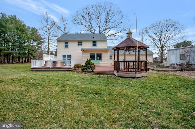 back of property featuring a wooden deck, a lawn, and a gazebo