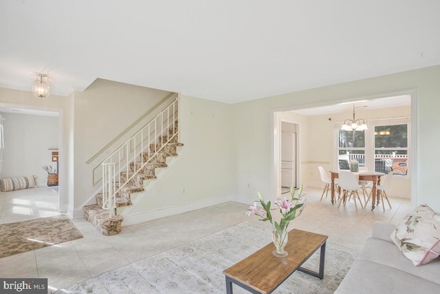 living area with an inviting chandelier, tile patterned flooring, stairway, and baseboards