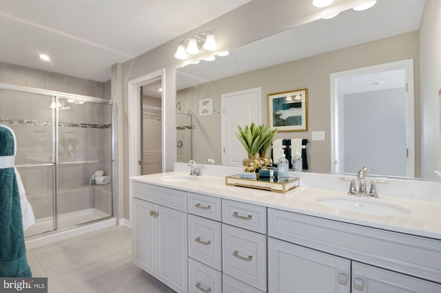 full bath with a stall shower, a walk in closet, a sink, and double vanity