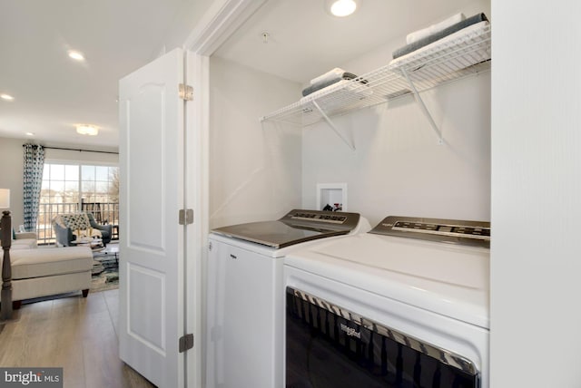 clothes washing area featuring laundry area, light wood finished floors, recessed lighting, and washer and dryer