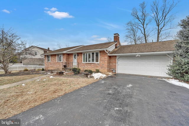 ranch-style home featuring aphalt driveway, brick siding, a chimney, fence, and a garage